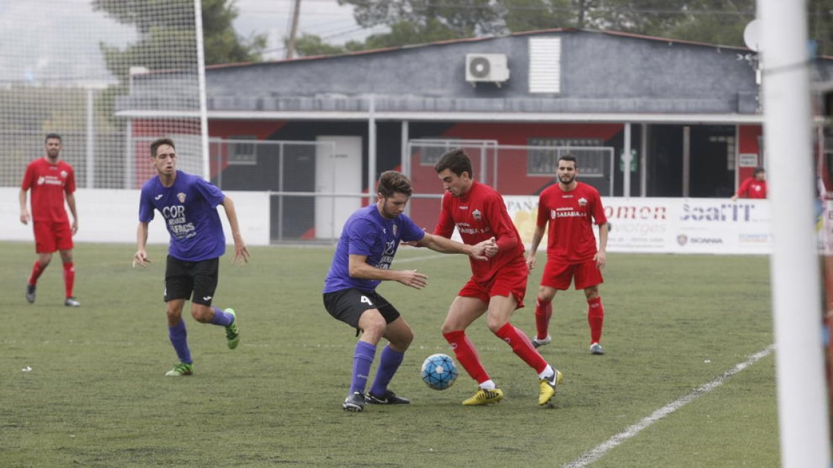 Un jugador de l’Alpicat i un altre del Jesús i Maria es disputen una pilota dividida.