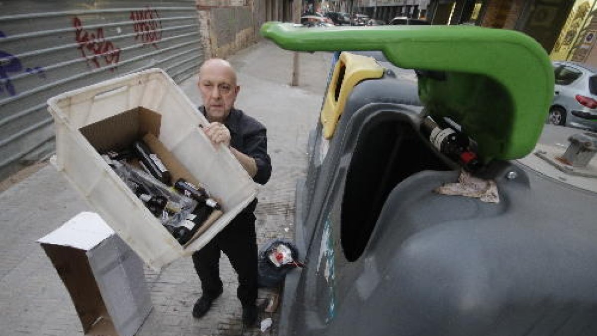 Un empleado de un restaurante de Lleida tirando envases de botellas al contenedor de reciclaje.