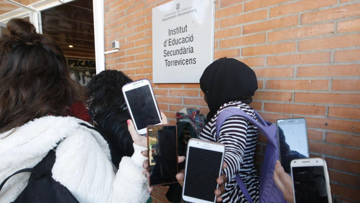 Alumnes del Torre Vicens mostren els mòbils a l’entrada de l’institut.