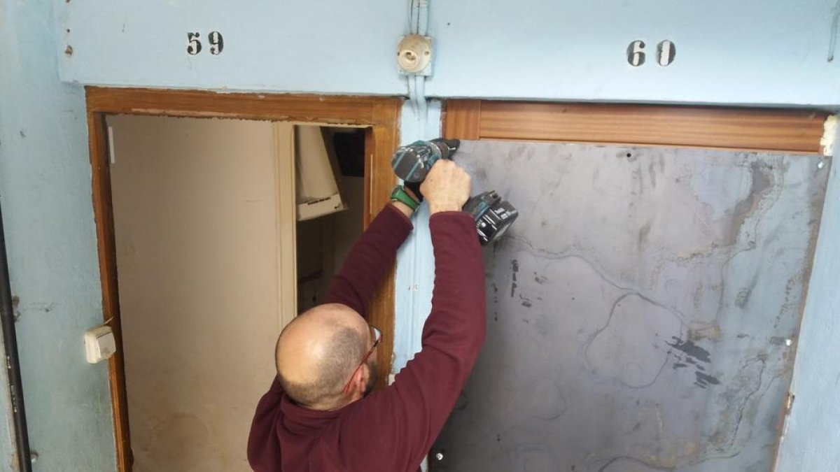 Un operario, colocando una plancha de metal en una puerta de uno de los pisos desalojados.
