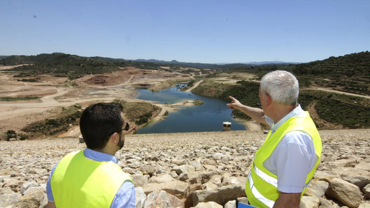 Josep Maria Serra (d.), al costat del responsable de l’empresa, mostra la zona inundada de la presa, amb uns 400.000 metres cúbics d’aigua.