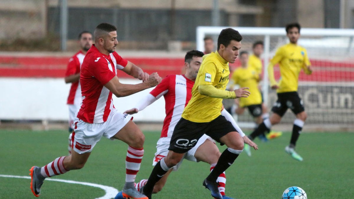 Dos jugadores del Tortosa intentan parar a uno del Lleida Esportiu B en una de las acciones del partido de ayer.