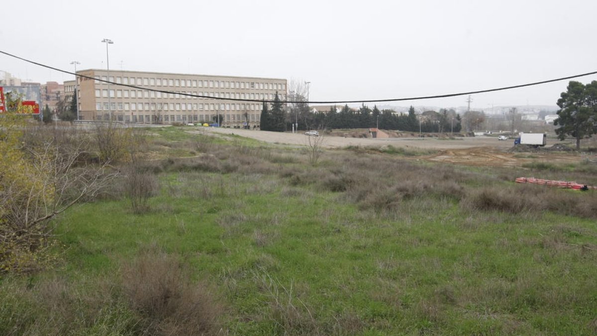 Vista dels terrenys on està previst el nou centre comercial, amb l’institut Joan Oró i el Camp Escolar al fons.