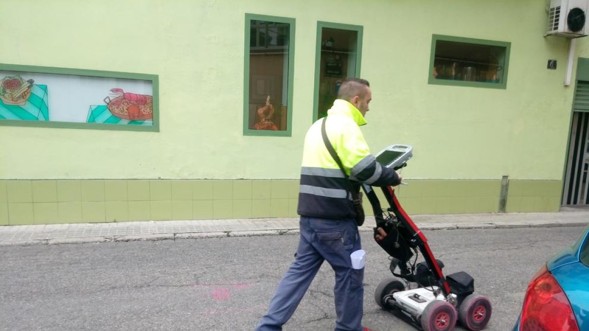 Un operario inspeccionando la ubicación y el estado de las tuberías, en Passatge Santa Isabel.