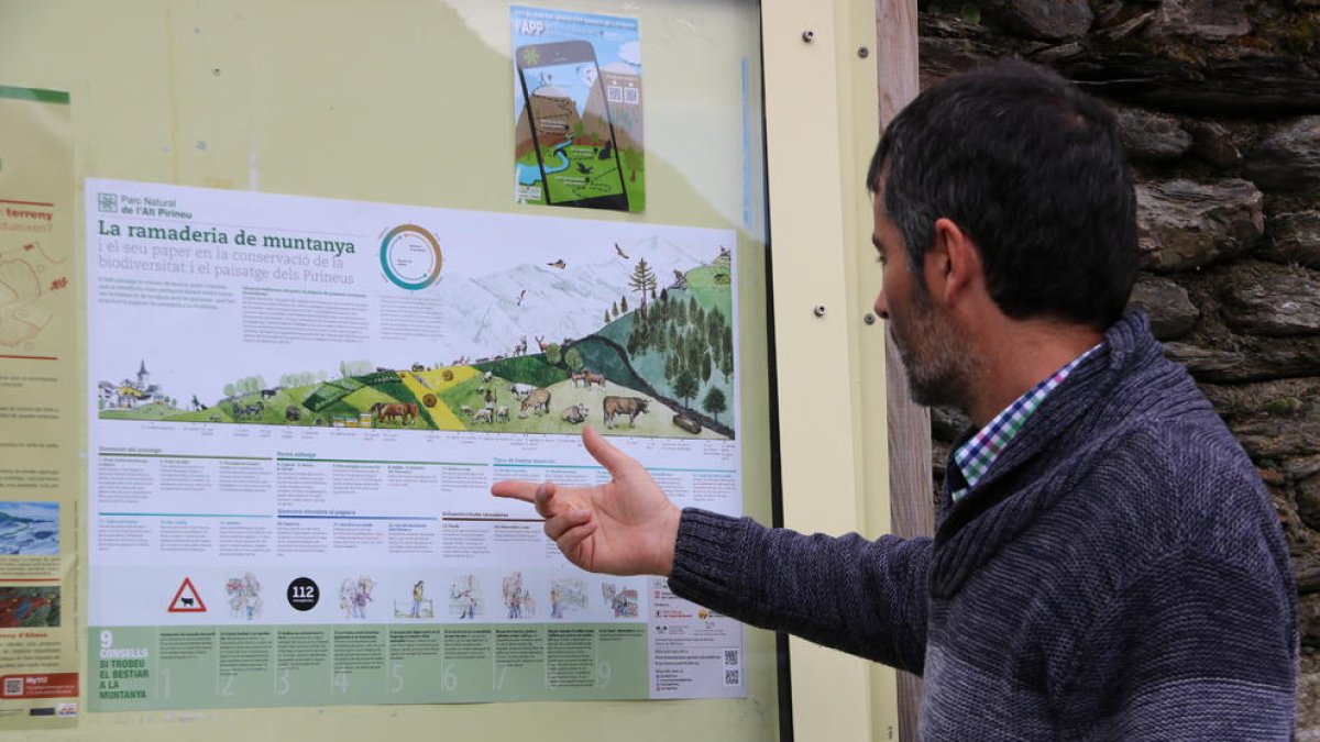 Una persona observando el cartel del Parc Natural de l’Alt Pirineu con los consejos y recomendaciones para los turistas. 