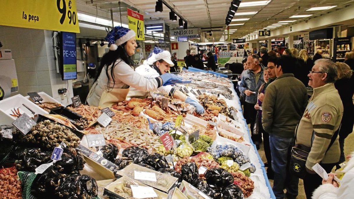 Imagen de clientes leridanos comprando pescado para la celebración de las fiestas navideñas.