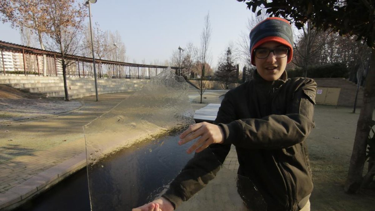 Un joven muestra una placa de hielo de uno de los pequeños estanques de los Camps Elisis de Lleida