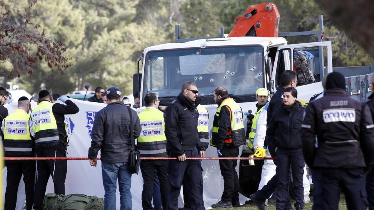 Autoridades y fuerzas de seguridad ante el camión con el frontal tiroteado.