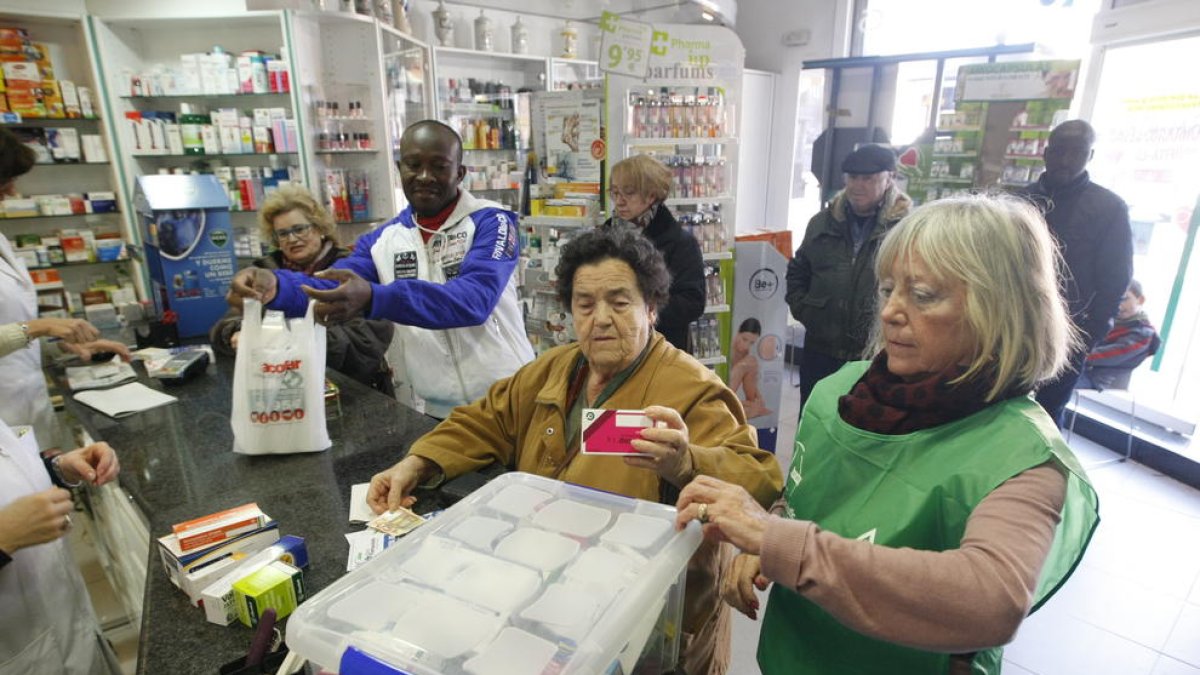 Voluntarios y una clienta solidaria, en la farmacia Isanta Crusellas.
