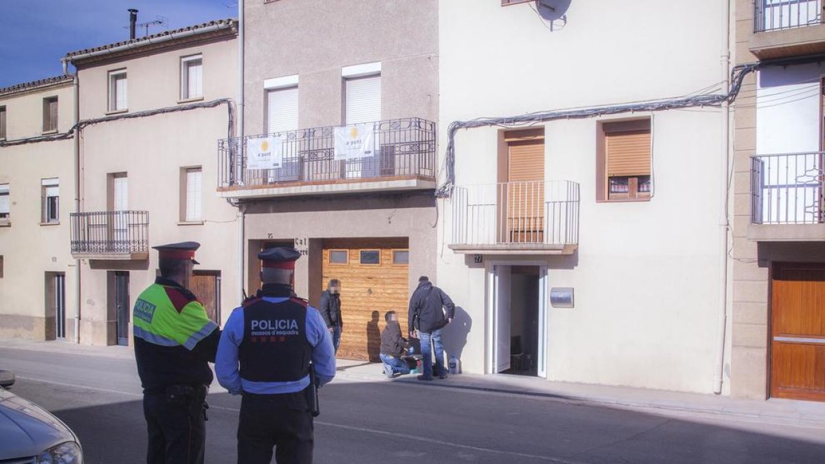 Mossos custodiant la casa on es va produir el succés, en primer pla, i agents d’investigació i de la científica, al fons.