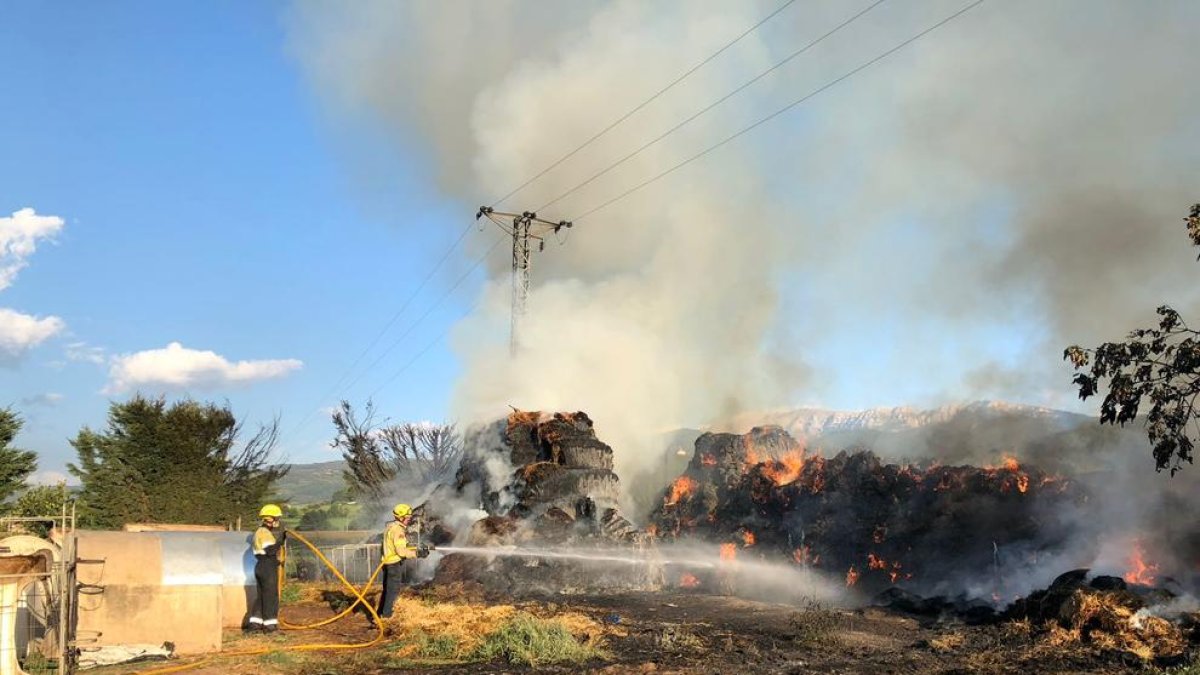 Bomberos trabajando junto a la paja en llamas. 