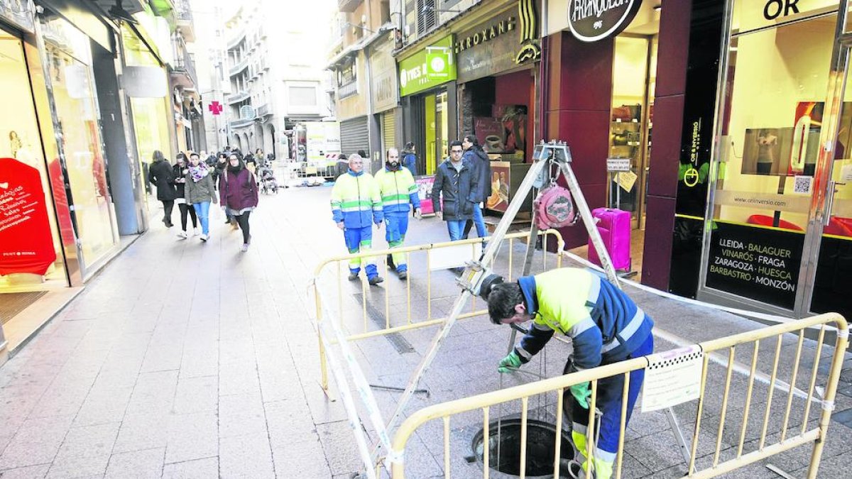 Un operario de Aigües Lleida trabajando en el alcantarillado en la calle Mayor.