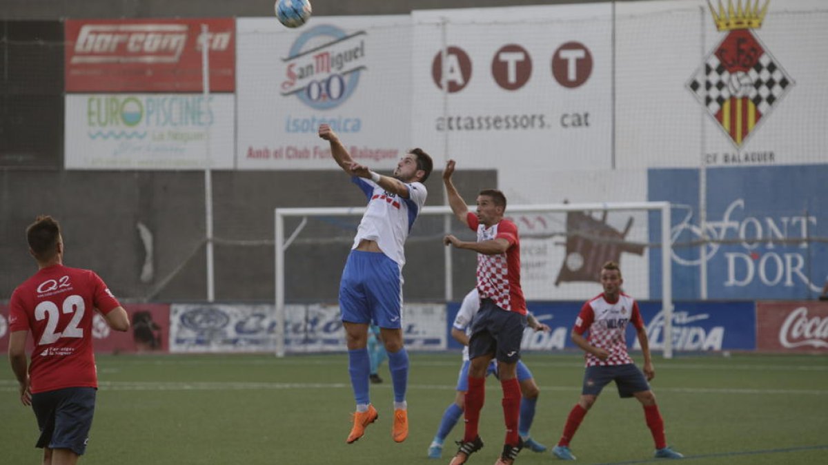 Un jugador del Mollerussa intenta controlar una pilota de cap davant de l’oposició d’un rival del Balaguer.