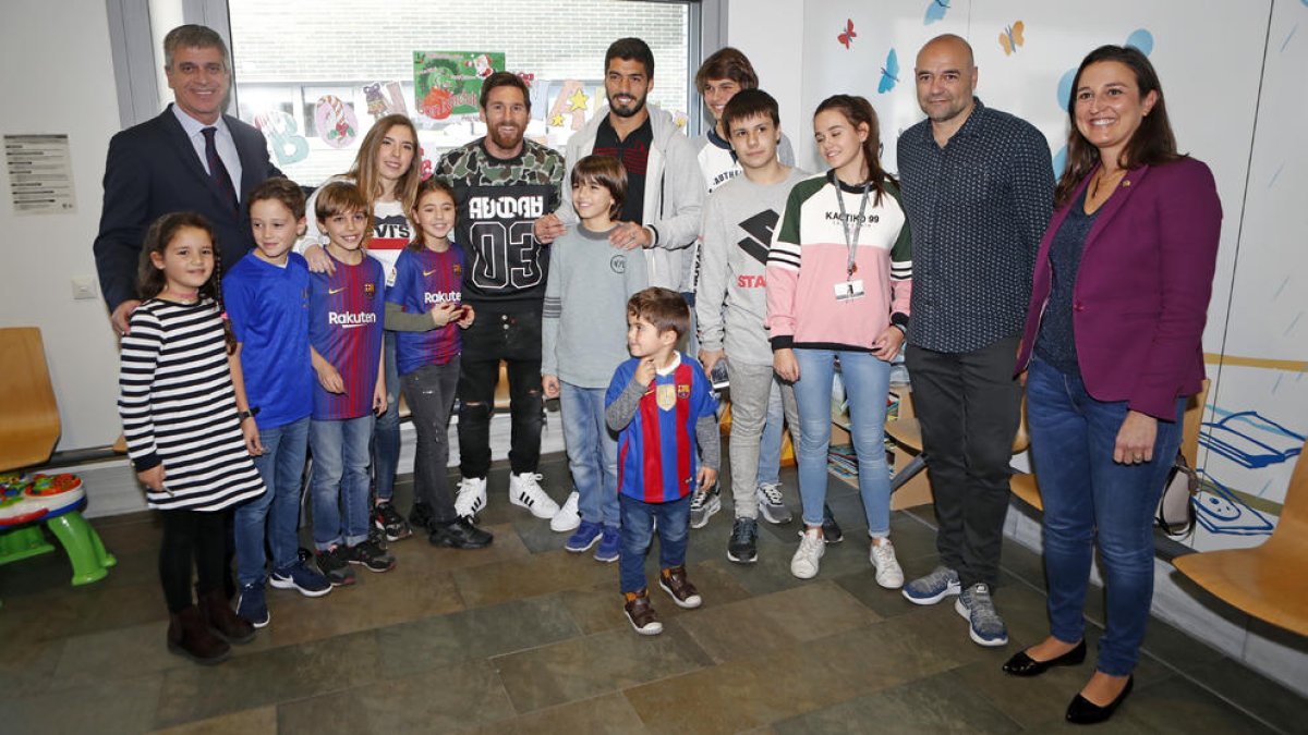 Messi y Luis Suárez, el directivo Jordi Mestre y padres y niños ayer durante la visita de jugadores del FC Barcelona a hospitales infantiles.