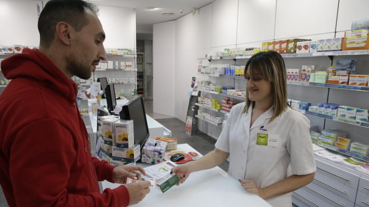 Una empleada d’una farmàcia a Balàfia ven un medicament a un client.