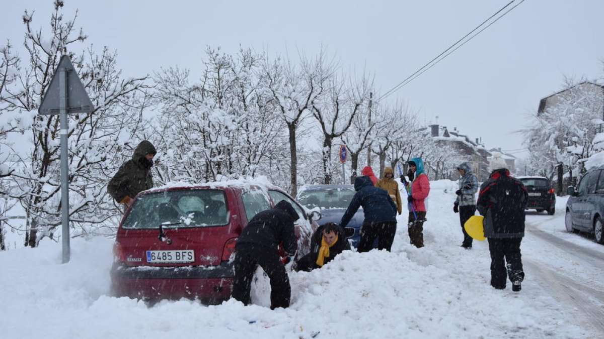 Afectados por la intensa nevada en Bellver de Cerdanya tratando de colocar cadenas a los vehículos.