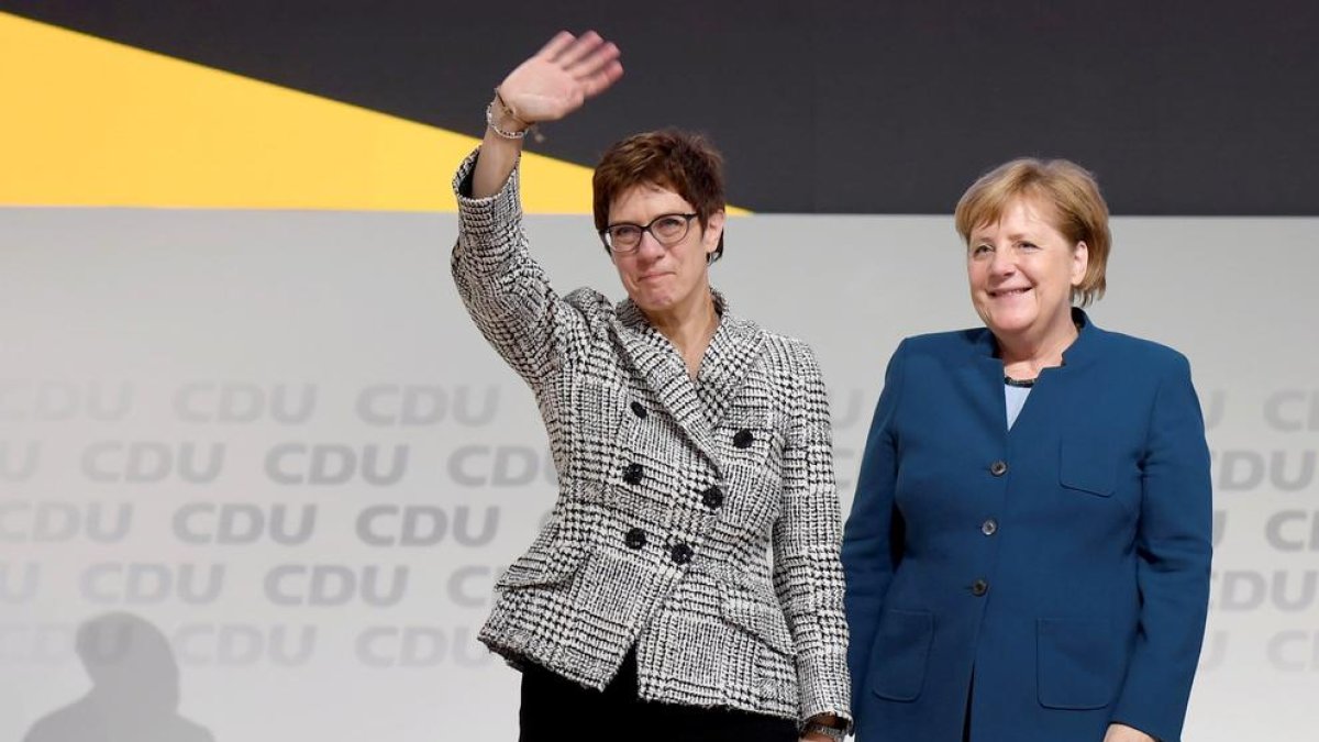 Annegret Kramp-Karrenbauer saluda a los militantes de la CDU acompañada de Merkel, ayer. 