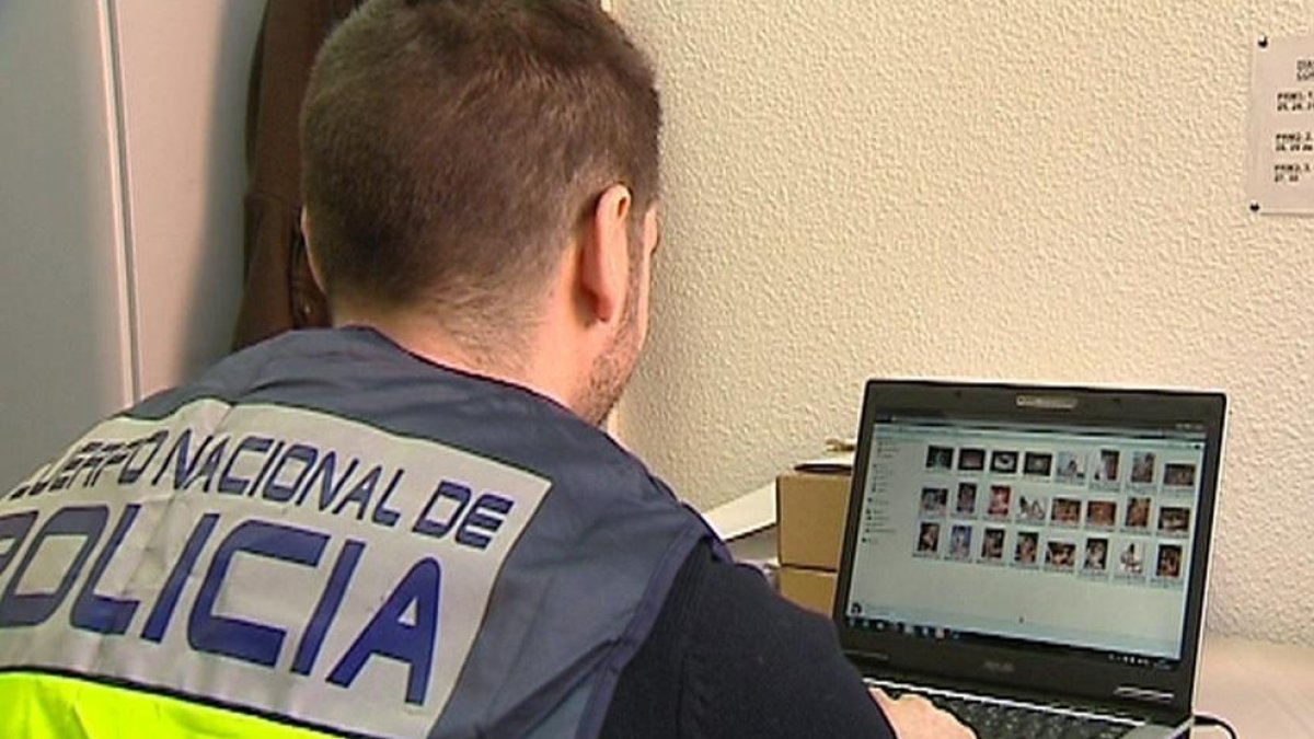 Un agente de la Policía Nacional revisa un ordenador requisado dentro de la operación.