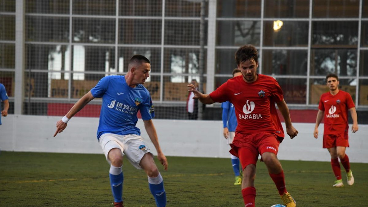 Un jugador de l’Alpicat intenta controlar una pilota davant de l’oposició d’un rival del Lleida B.