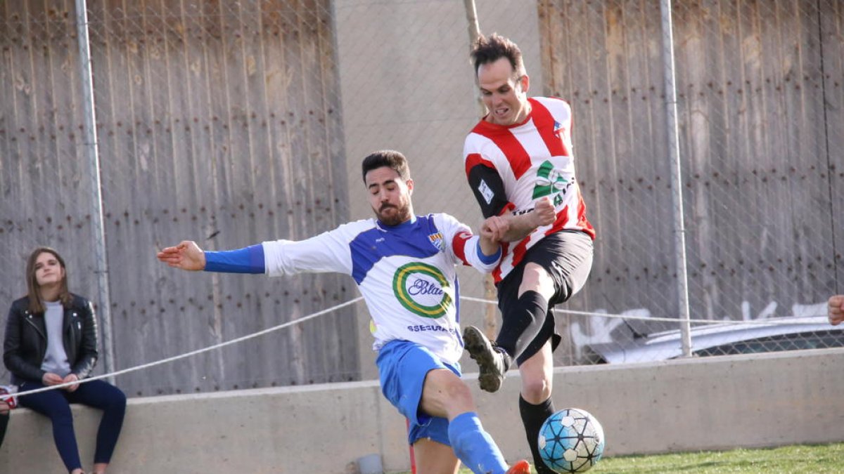 Un jugador del Bellcairenc golpea el balón pese a la presión rival.