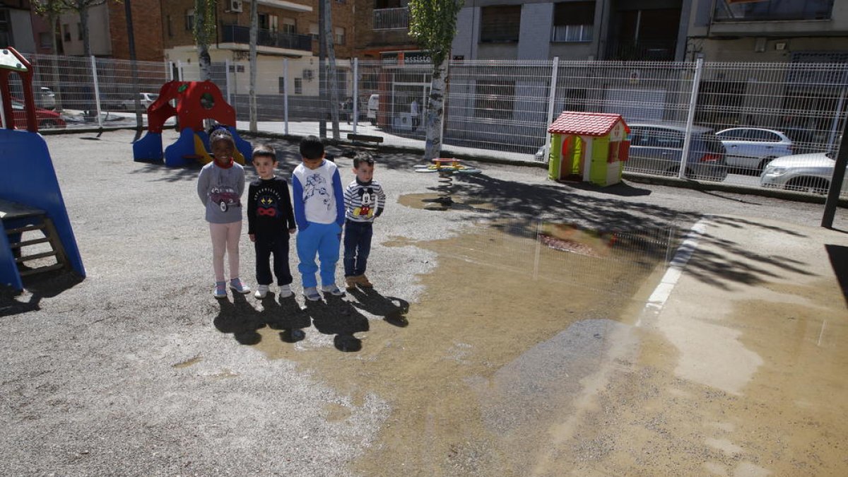 Un grupo de niños de P-3 en el anegado patio de la escuela Joan Maragall.