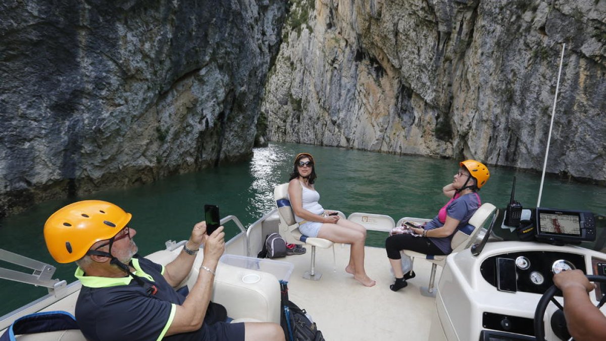 Turistas surcando el congosto de Mont-rebei ayer por la tarde.  En la foto inferior a la derecha el barco pasando por debajo de la pasarela peatonal sobre el río.