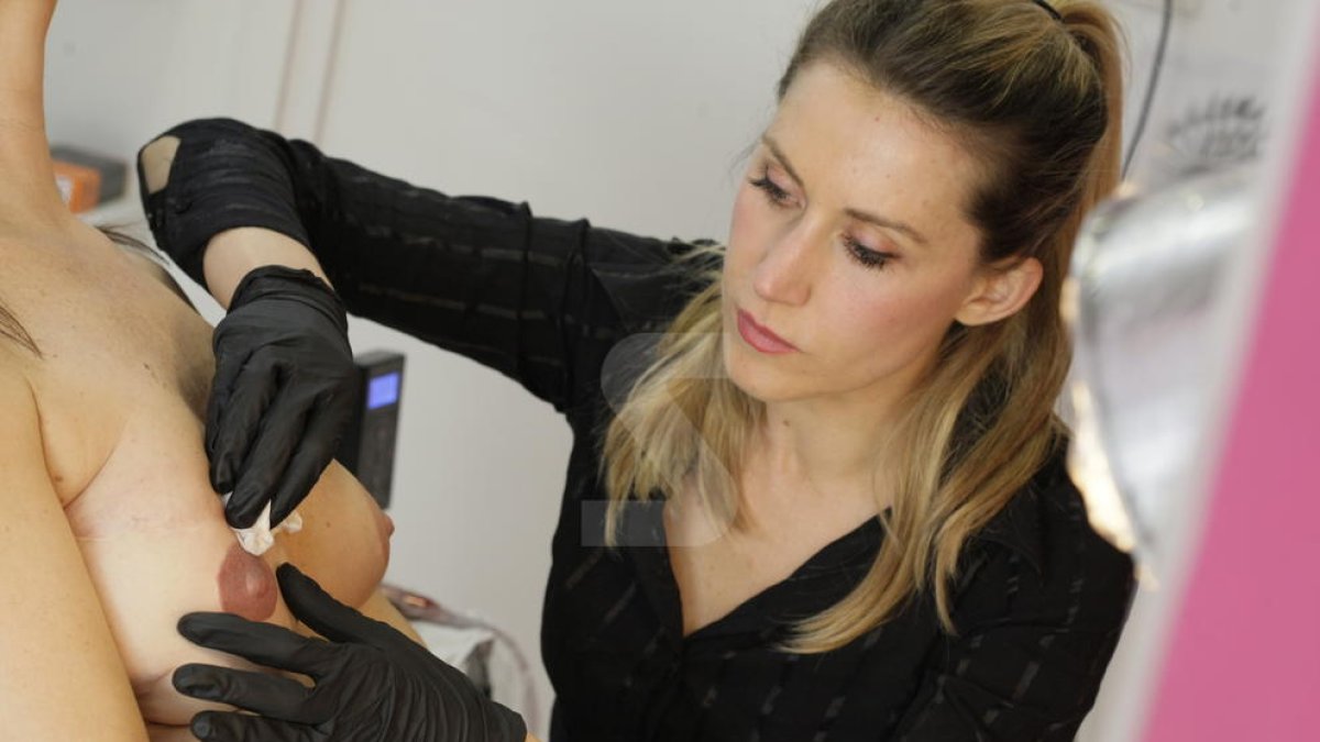 Una tatuadora realitza micropigmentació a una afectada per càncer de mama.