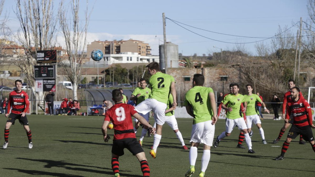 El jugador visitante Fabregat se eleva por encima del resto para despejar de cabeza, ante la presencia de Traguany y del local Jordi Martí.