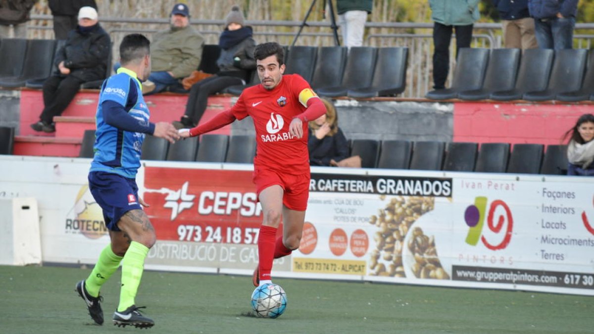 El capità de l’Alpicat, Xavi Gomà, condueix l’esfèric davant l’oposició d’un jugador de l’Igualada.