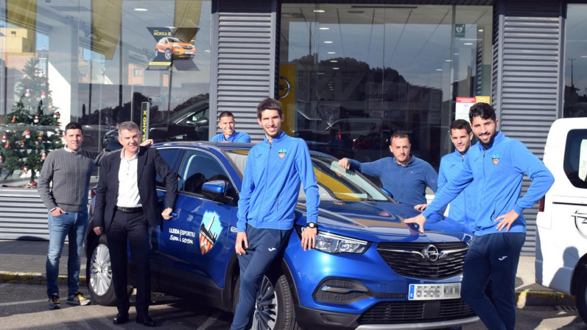 Algunos jugadores y técnicos posan ayer con los vehiculos que Opel Lleidamobil cede al club.