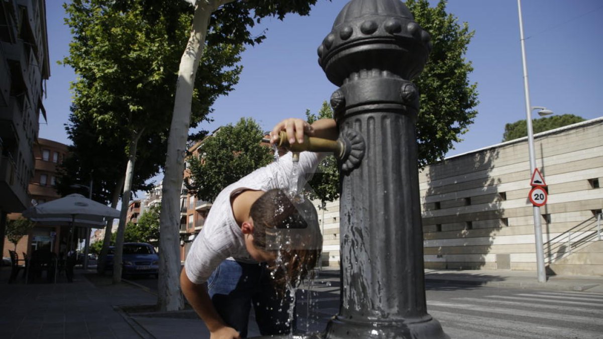Un nen es refresca en una font en plena onada de calor a Lleida.