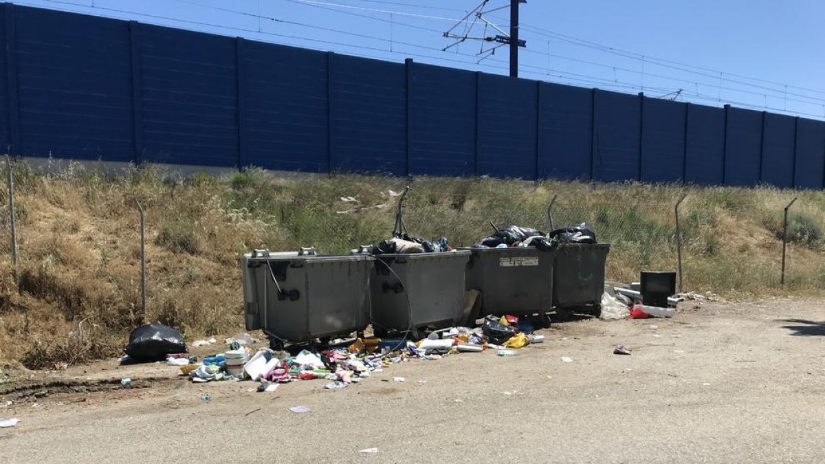 Imagen de los contenedores y la basura junto a las vías del tren.