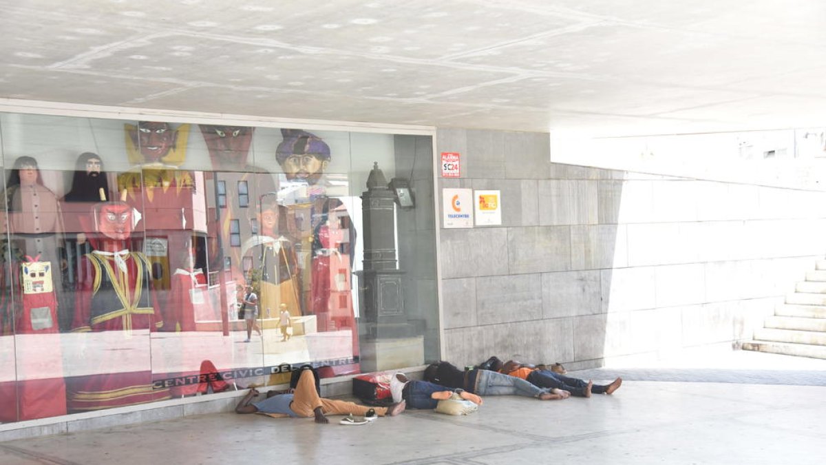 Un grupo de inmigrantes durmiendo en la parte sombreada del centro cívico de plaza l’Ereta, ayer. 