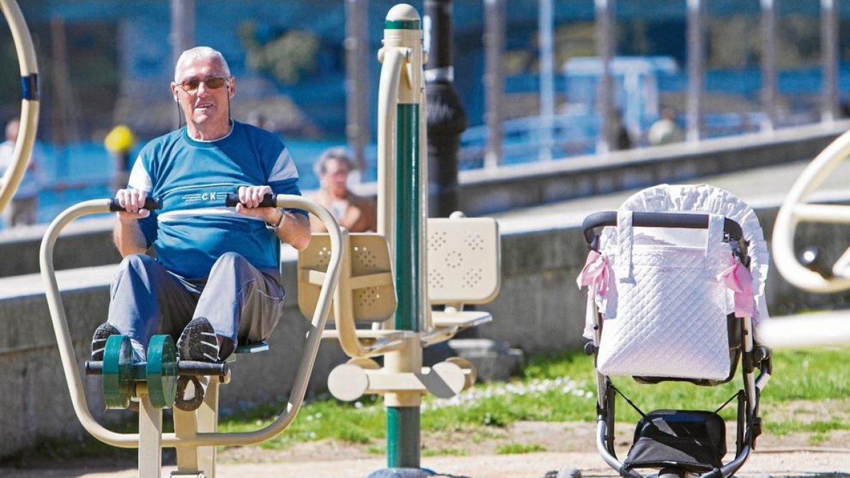 Un pensionista fa exercici en un parc públic mentre cuida la néta