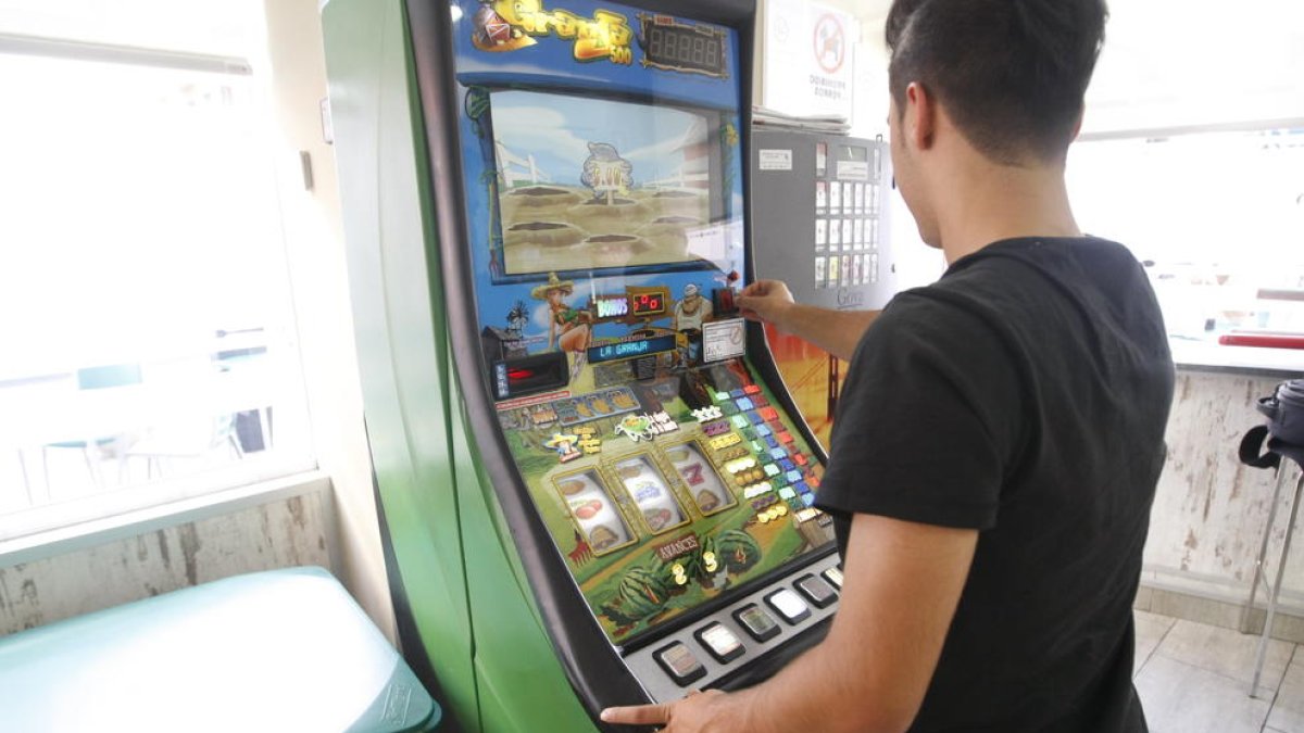 Un usuari jugant a una màquina escurabutxaques en un bar de Lleida.