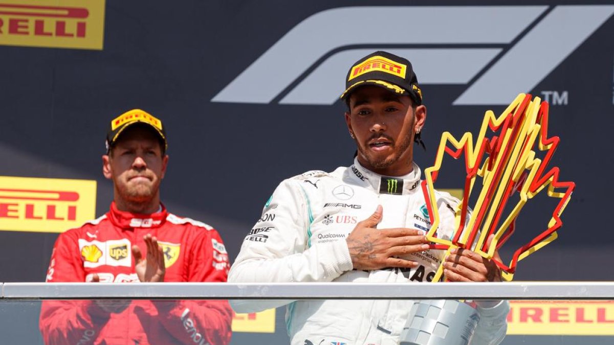 Hamilton, al podi amb el trofeu de guanyador, i Vettel, darrere, resignat per la sanció rebuda.