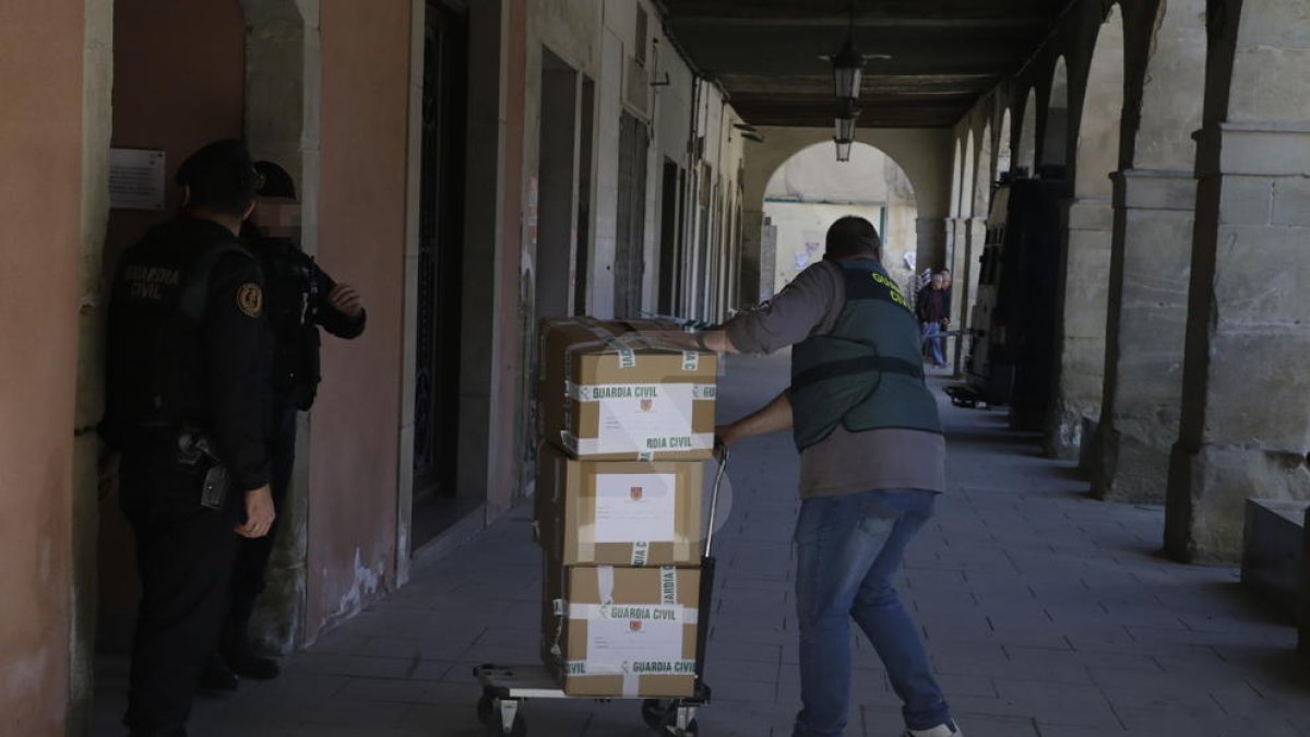 Un agent de la Guàrdia Civil treu caixes amb documents de l'edifici de l'ajuntament d'Almacelles.