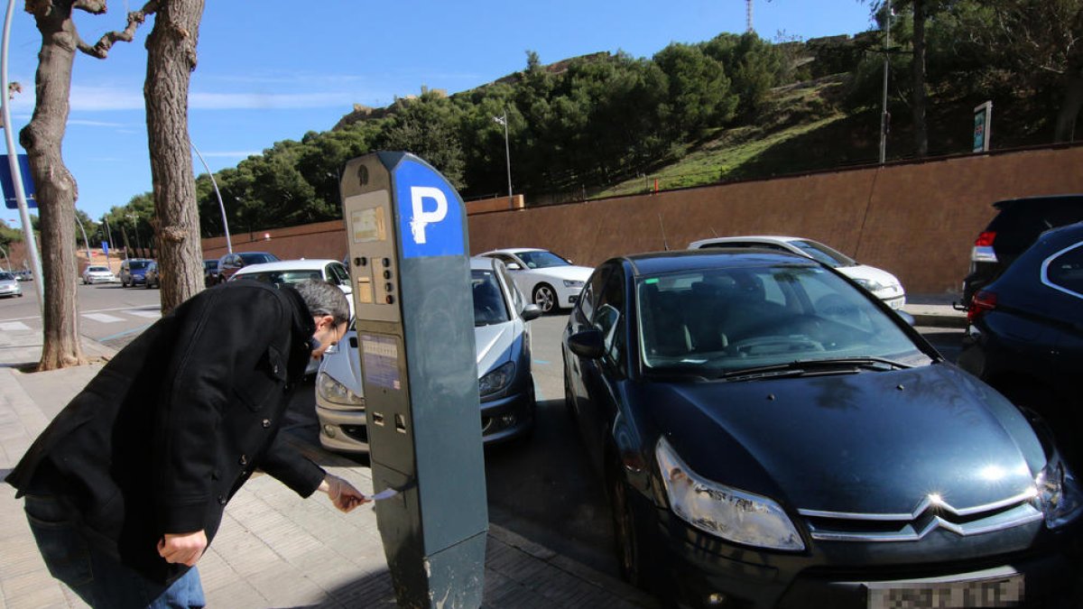 Un ciudadano recoge el tiquet tras aparcar en una zona azul. 
