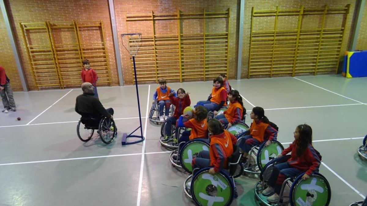 Nens d’un col·legi de Lleida practicant bàsquet en cadira de rodes.