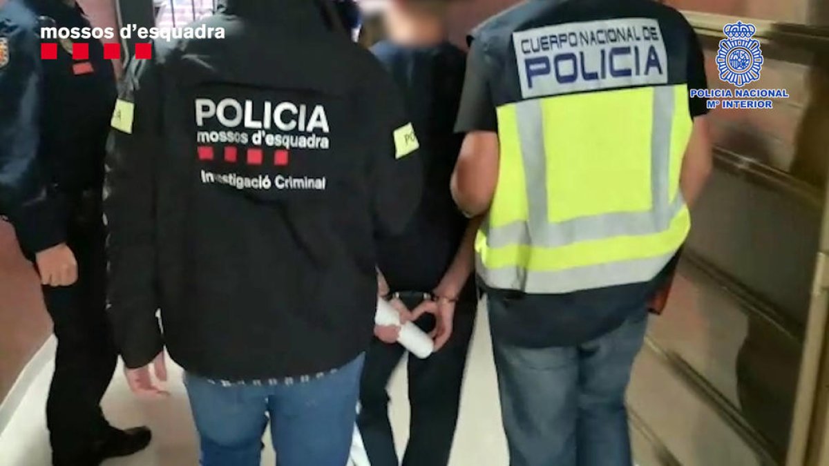 Los agentes llevándose a uno de los siete detenidos.