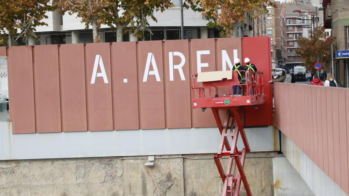 Operarios tapando ayer las grandes letras del rótulo de “A.Areny” de la pasarela de los Maristes.