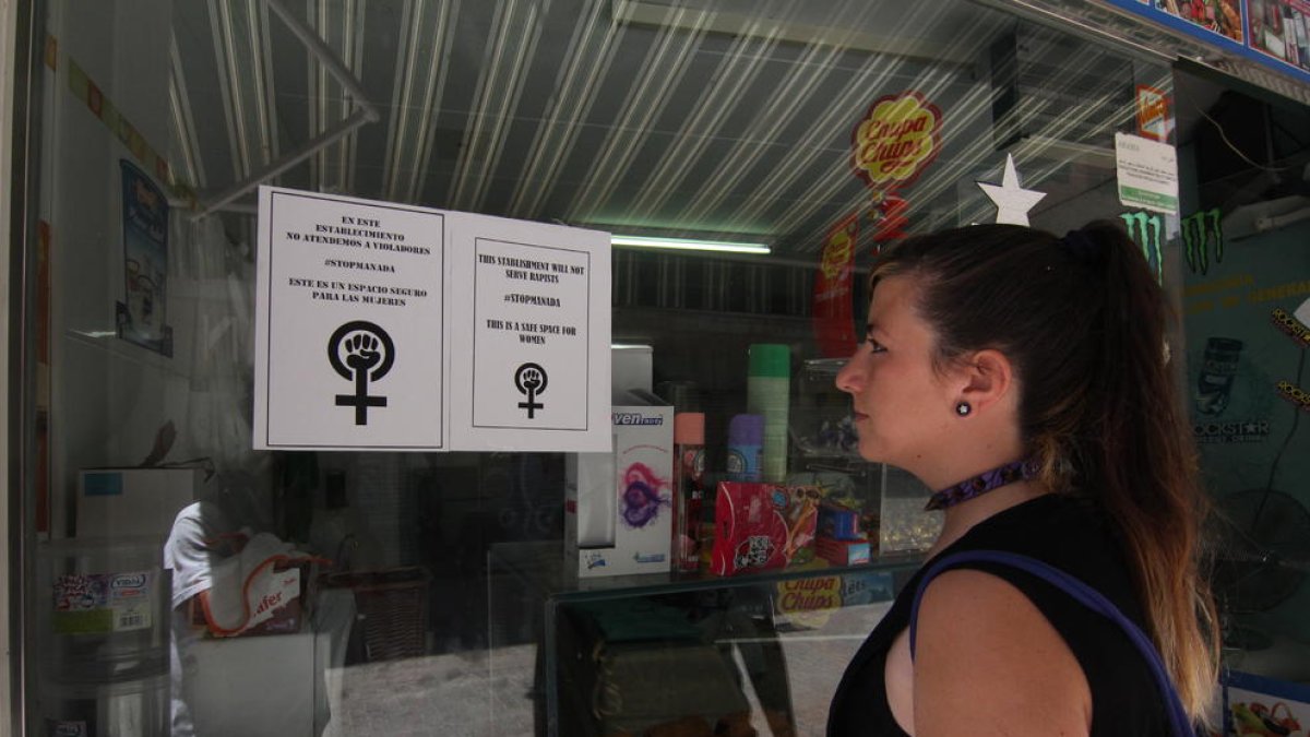 Un mujer mira ayer uno de los carteles colgados en un establecimiento de la calle Cardenal Remolins.