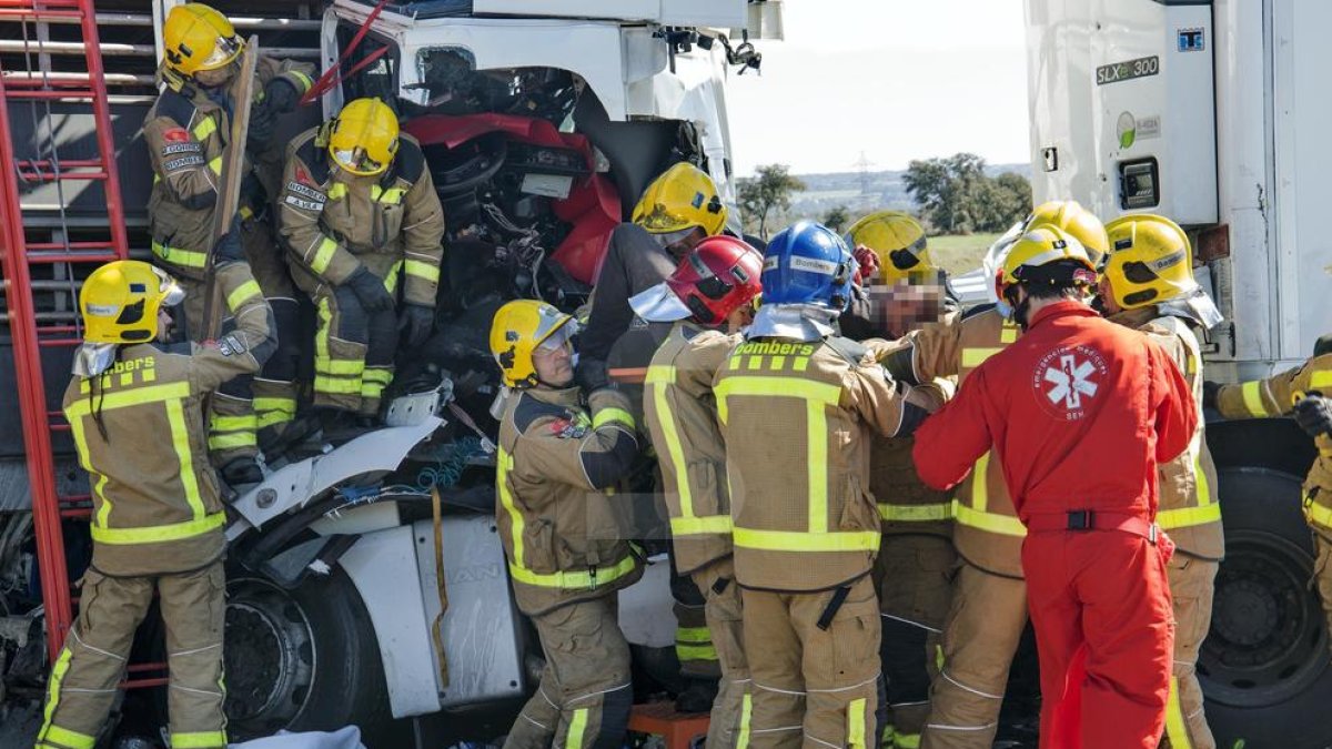 Els serveis d'emergència rescaten el conductor atrapat al seu vehicle després del xoc.