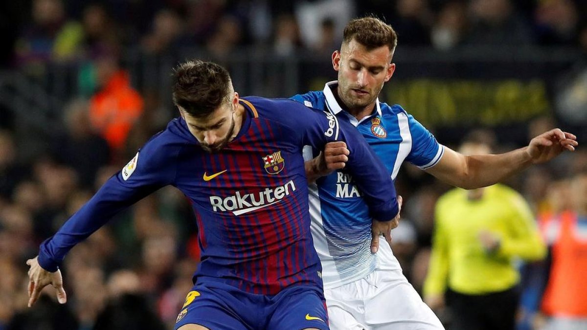 Gerard Piqué protegeix la pilota davant de Leo Baptistao.