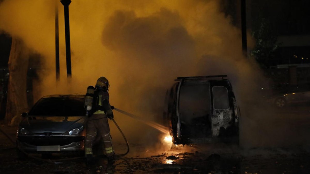 Un bombero apagando las llamas de la furgoneta que se calcinó.