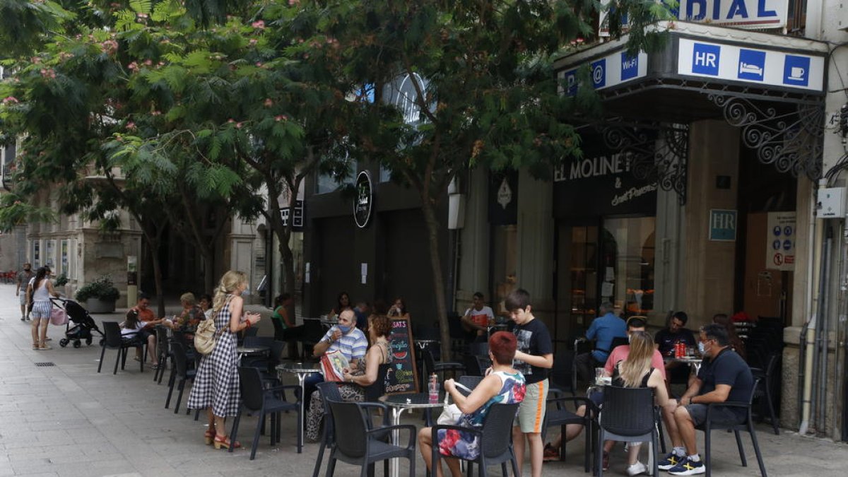 Imagen de una terraza de un bar con clientes junto a la plaza Sant Joan de Lleida ciudad.