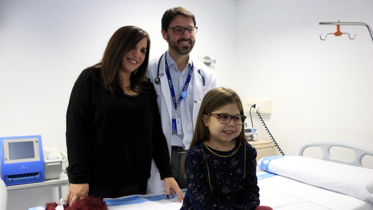 Iría, la niña de diez años con una enfermedad ultra-rara que ha sido trasplantada de corazón, hígado y riñón en el Vall d'Hebron, con su madre, Judith, y el doctor Jesús Quintero, a la consulta.