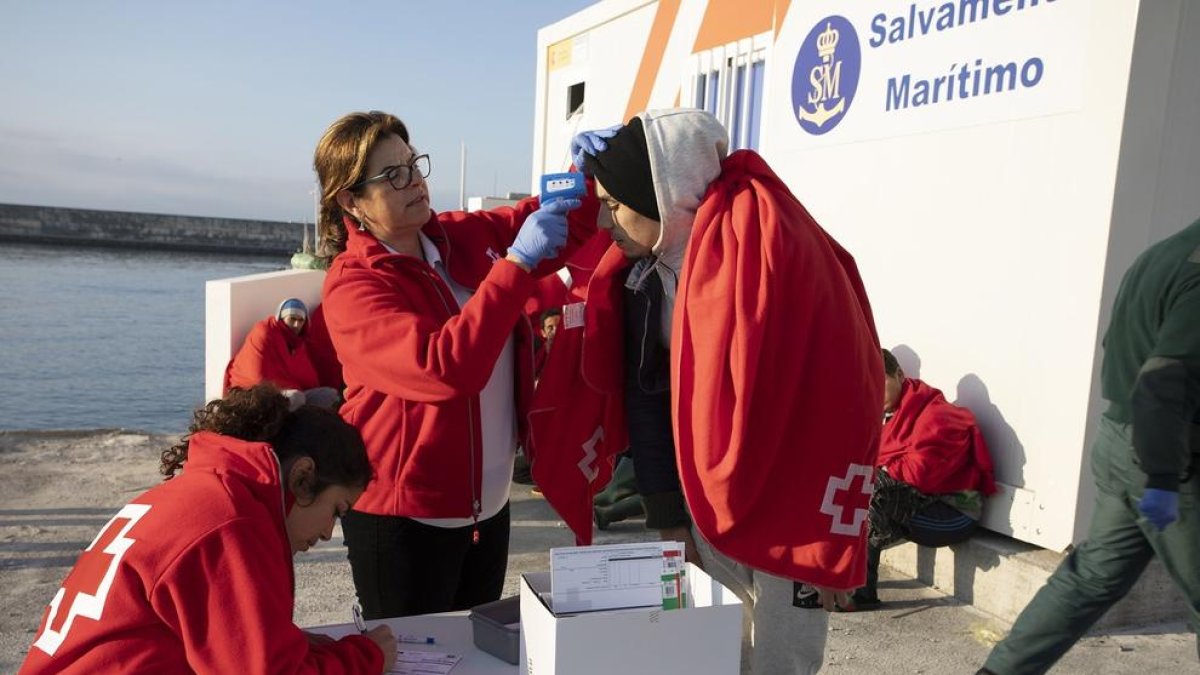 Personal de Creu Roja pren la temperatura a una migrant.