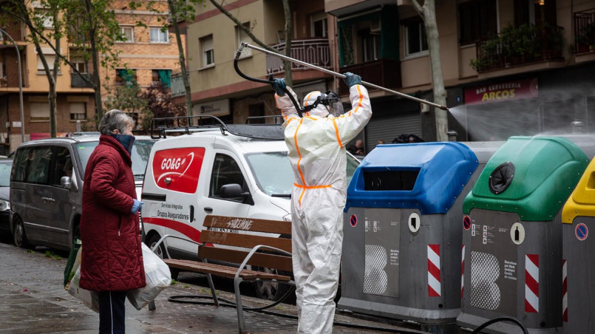 Un operario desinfectando un cubo de basura en Barcelona.
