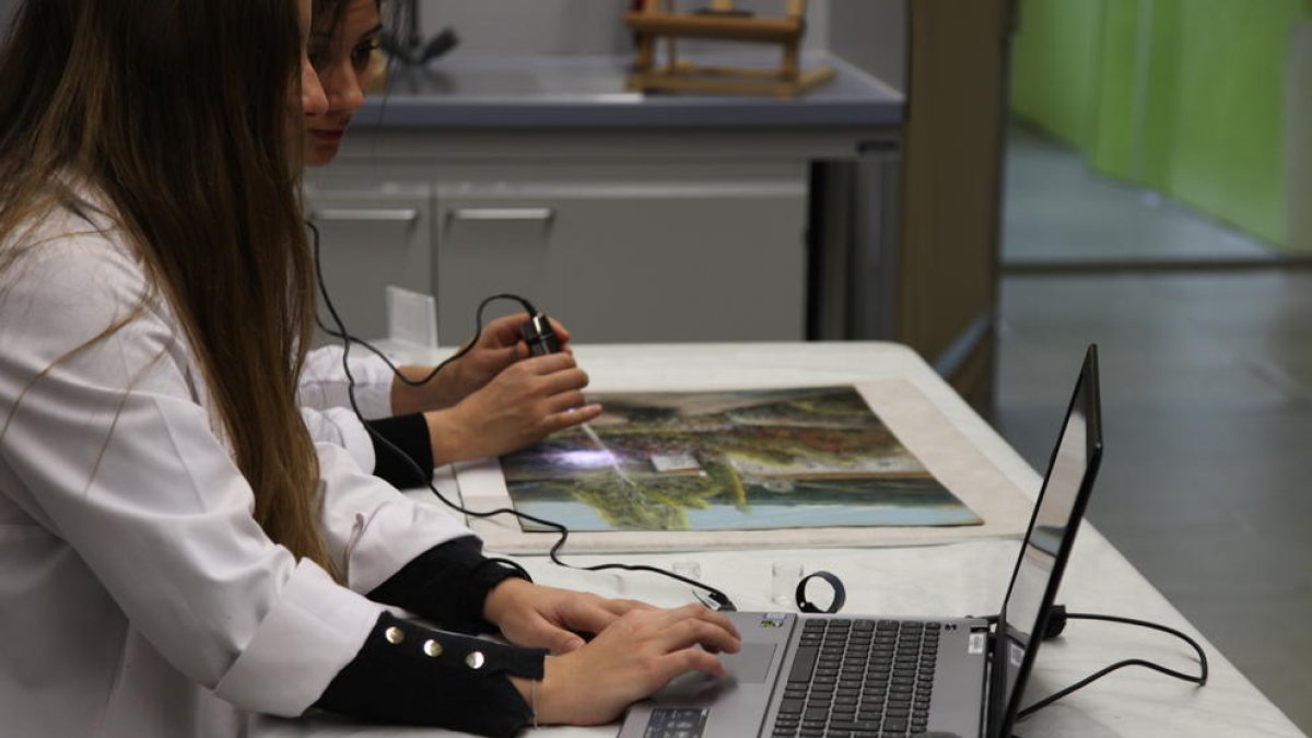 Dos investigadores del CAEM, Mariona Navarro i Jessica Martí, examinen la textura de la pintura.
